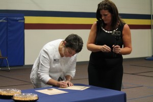 Dr. Trina Boteler signs the agreement as Jennifer Hernandez looks on during the school's PTSA meeting.