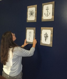 CTC student Jamie Yoh hangs nautical-themed pictures on the wall.