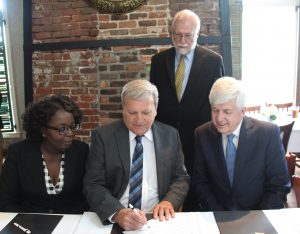 Photo of Bartow County Commissioner Steve Taylor signs an agreement recognizing the swearing in of new CTC board members Shenelle Gordon, human resources manager for Voestalpine Automotive Components Cartersville, Inc. (left); and Jim Hawk, Toyo Tire president and chairman (right). CTC President Dr. Ron Newcomb looks on from behind.