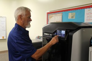 Photo of Drafting Technology instructor Jack Reece setting the Stratasys F270 printer for a new print job.