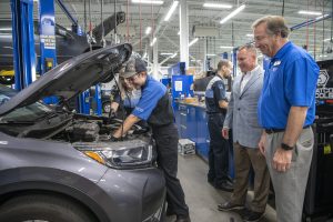General Managers watch as CTC interns work on vehicle.