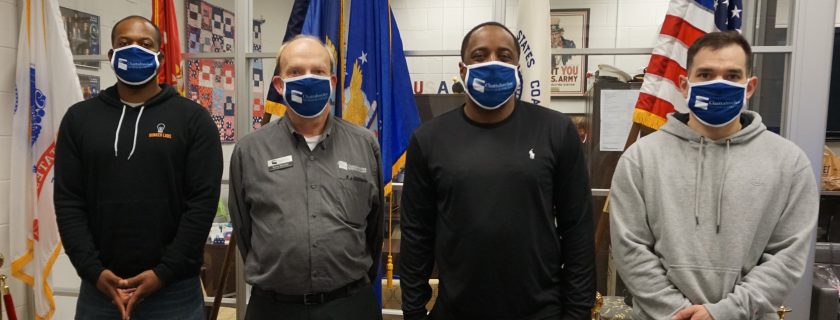 Four Chatt Tech veteran students are shown here in front of flags