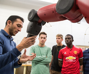 Instructor and three men with a robot