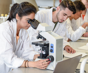 Students in lab coats working with microscopes