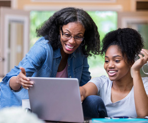 Parent and student smiling and using a laptop