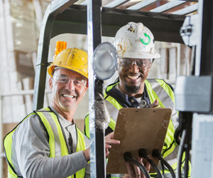 Two men in hardhats smiling at work