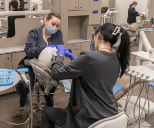 Dental assisting students working on a practice doll with teeth