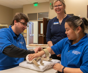 Student and instructor smiling and practicing OTA curriculum on a fellow smiling student