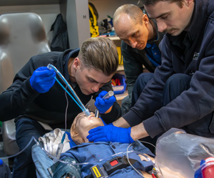 Paramedicine students and instructor using life support medical equipment on a mannequin