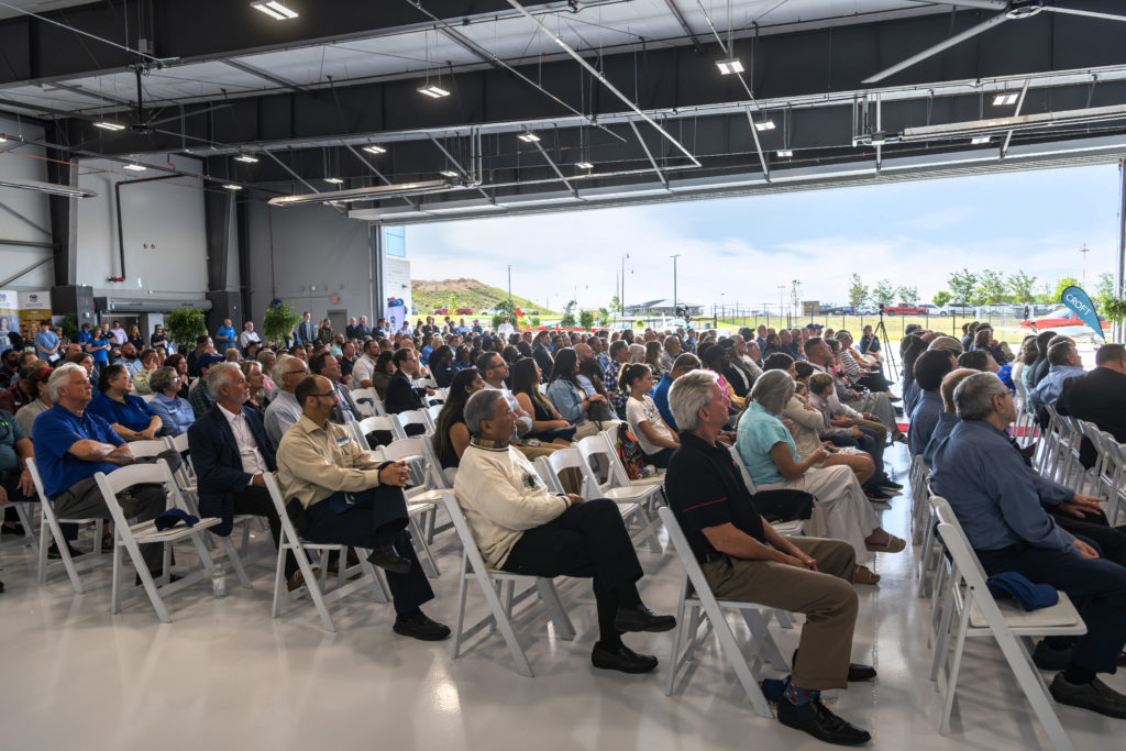 Hundreds of people are seated in the hangar for the ribbon-cutting ceremony