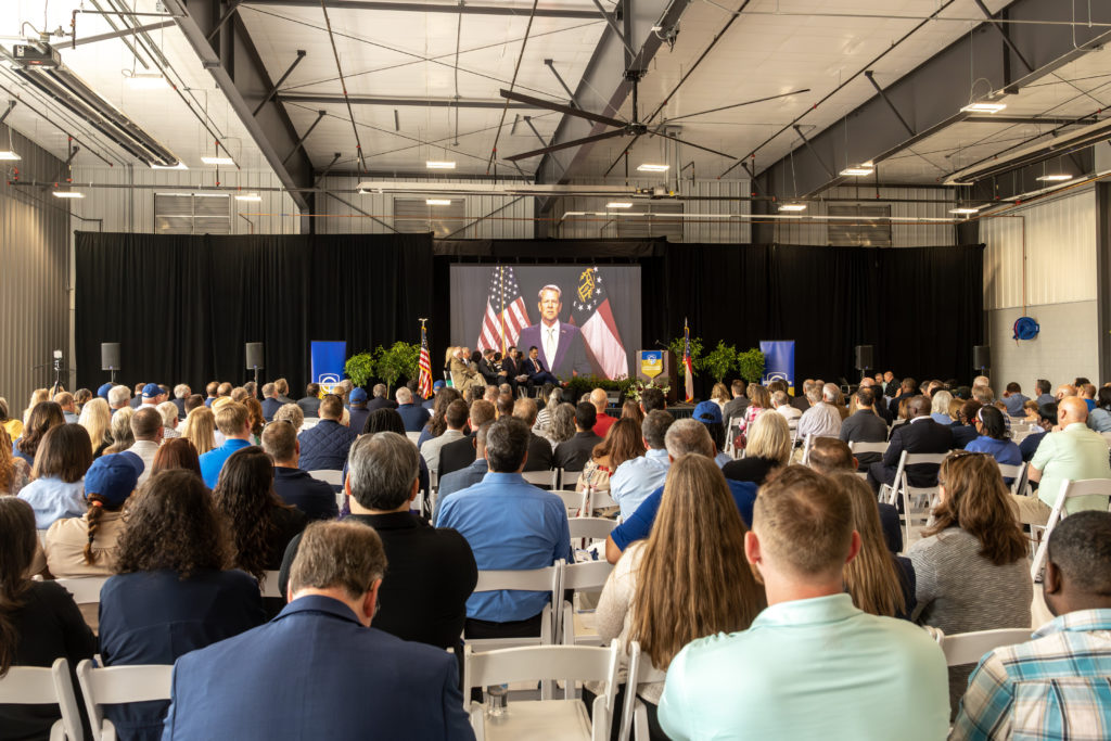 Hundreds of people listen to video message from Gov. Brian Kemp at the ribbon-cutting event