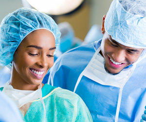 One man and one woman surgical techs stand side-by-side, smiling